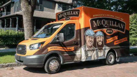 A McQuillan Bros plumbing service van for general heating repair is parked on a residential street. The van, in vibrant orange and brown, showcases illustrations of two diligent workers on its side.
